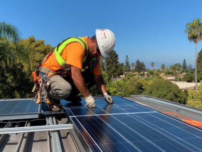 technician installing solar panels on a roof, focused on securing the panels with tools while adjusting the positioning for optimal placement, bright sunlight casting sharp shadows across the roof and panels, clear blue sky in the background, with the technician wearing protective gear, harnessed for safety, and surrounded by the clean lines of the modern rooftop, atmosphere of sustainability, precision, and innovation, outdoor construction photography, captured with a Canon EOS R6 and 24-70mm f/2.8 lens to emphasize detail and the bright lighting on the panels --ar 16:9 --profile kwllwrr --stylize 250 --v 6.1 Job ID: 4ffd38ad-f15e-4eb7-afb3-97dcccfb4d31