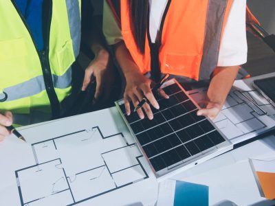 Closeup of team of industrial engineers meeting analyze machinery blueprints consult project on table in manufacturing factory. Working in manufacturing plant or production plant.